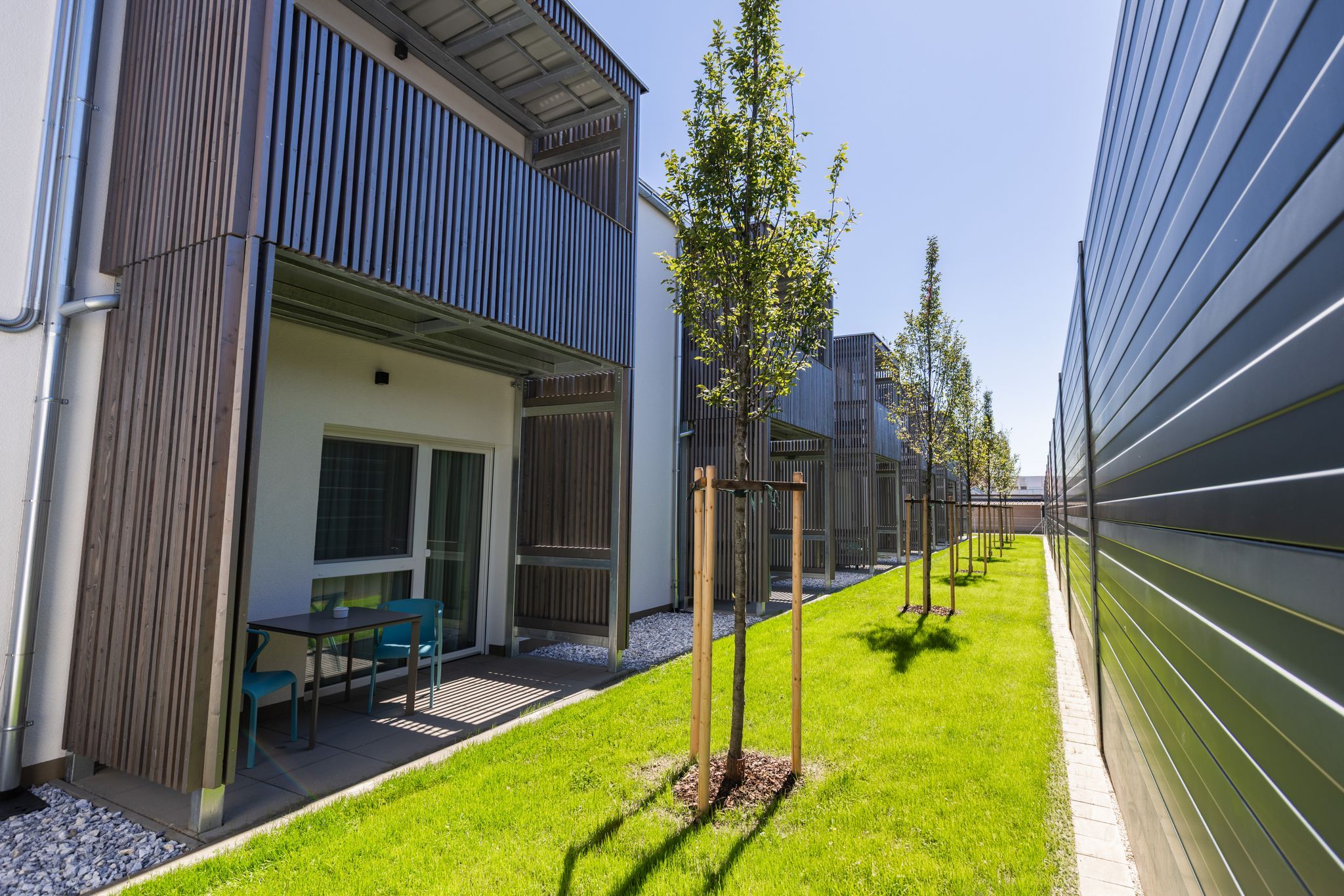 Modern apartment complex with balconies and a well-maintained lawn.