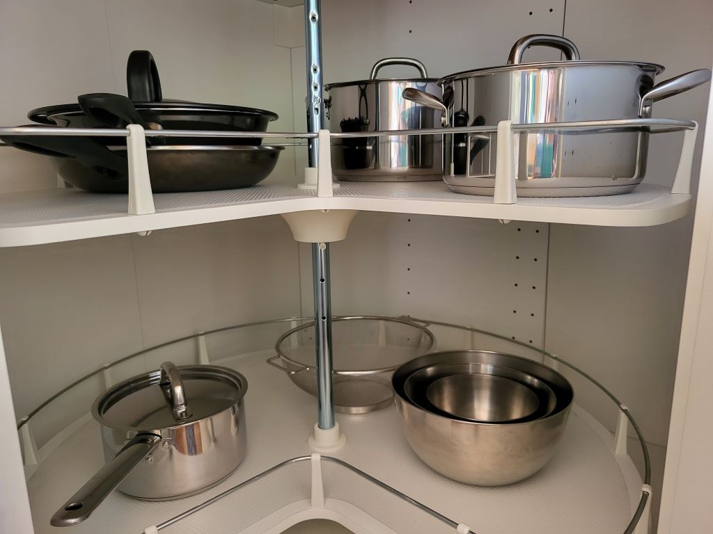 Kitchen cupboard with pots and pans on rotating shelves.