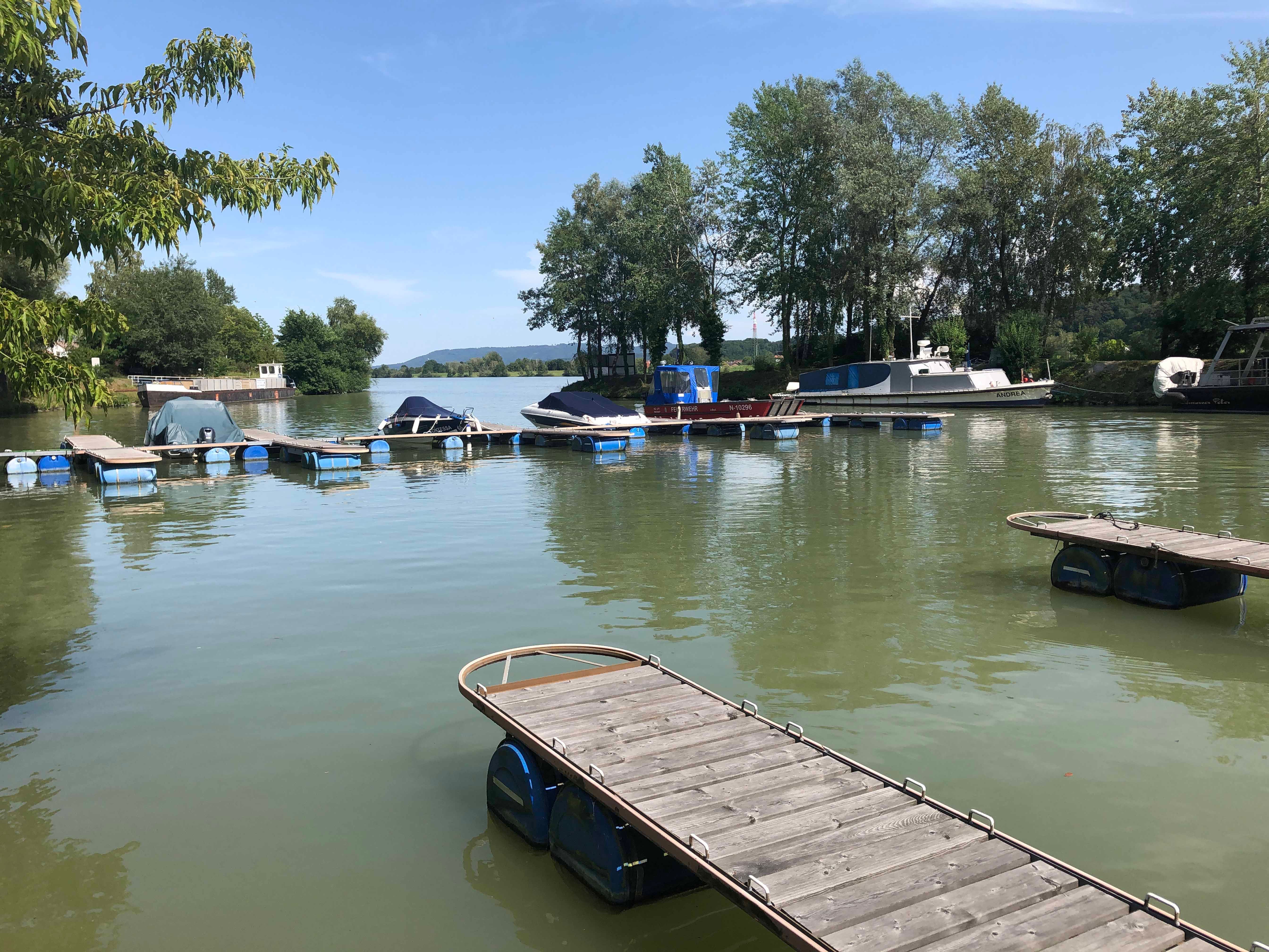 Boats in the harbor of Marbach am Neckar, surrounded by trees and jetties.