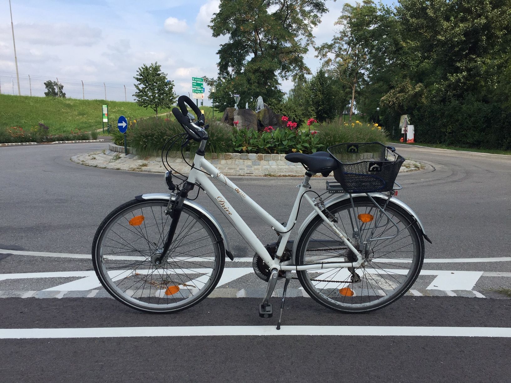 Bicycle on a road in front of a traffic circle in Tulln, surrounded by flowers and trees.