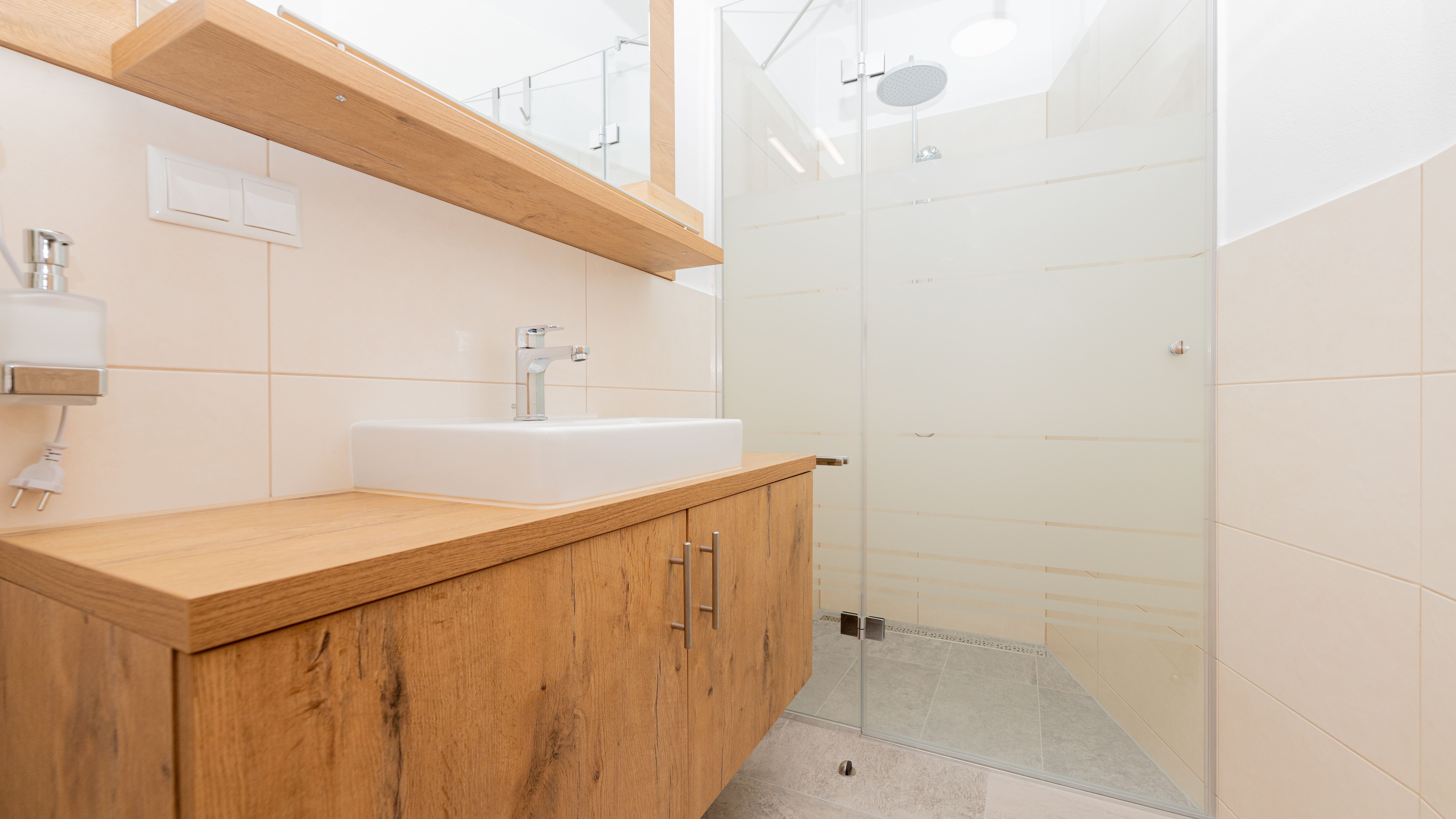 Modern bathroom with wooden washbasin and glass shower.