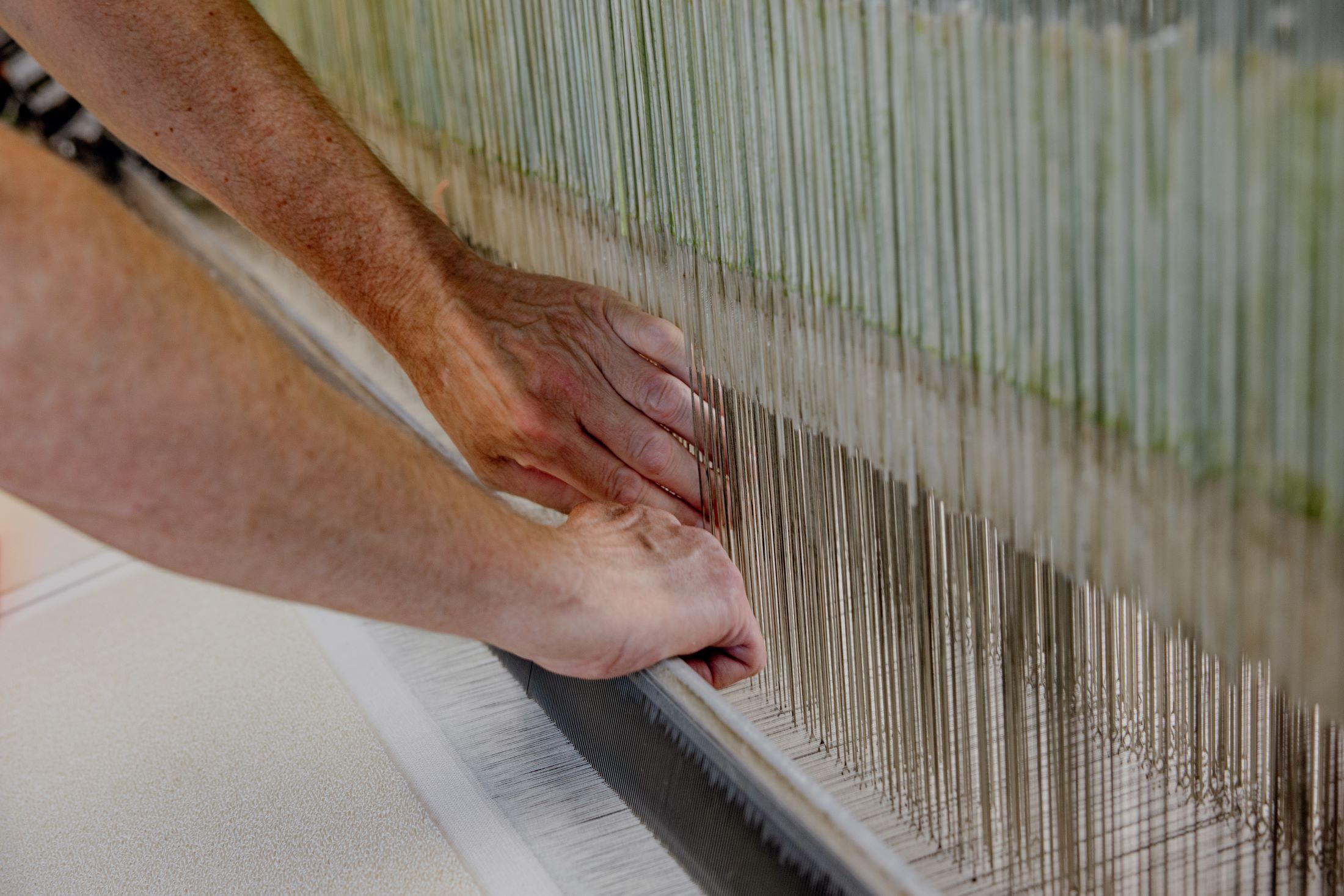 Close-up of hands working on a loom.