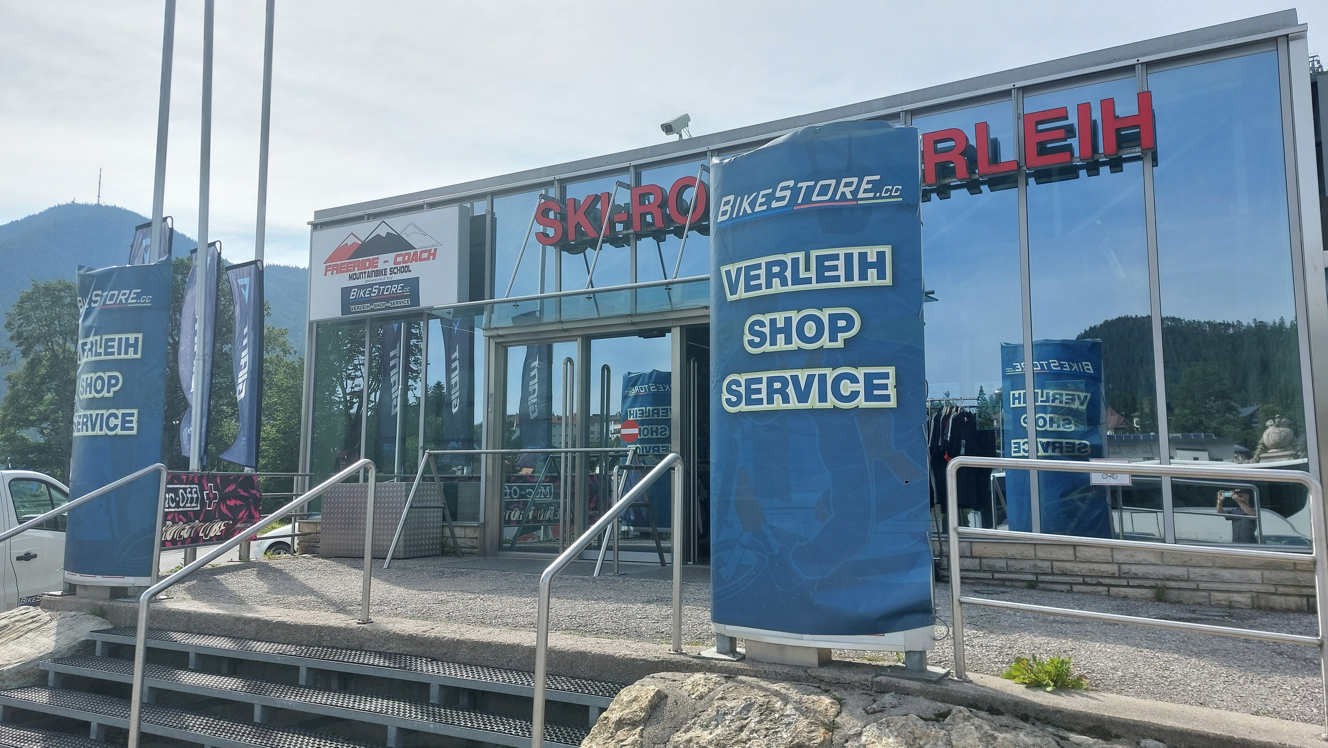 Entrance to a sports store with rental, store and service. Mountains in the background.