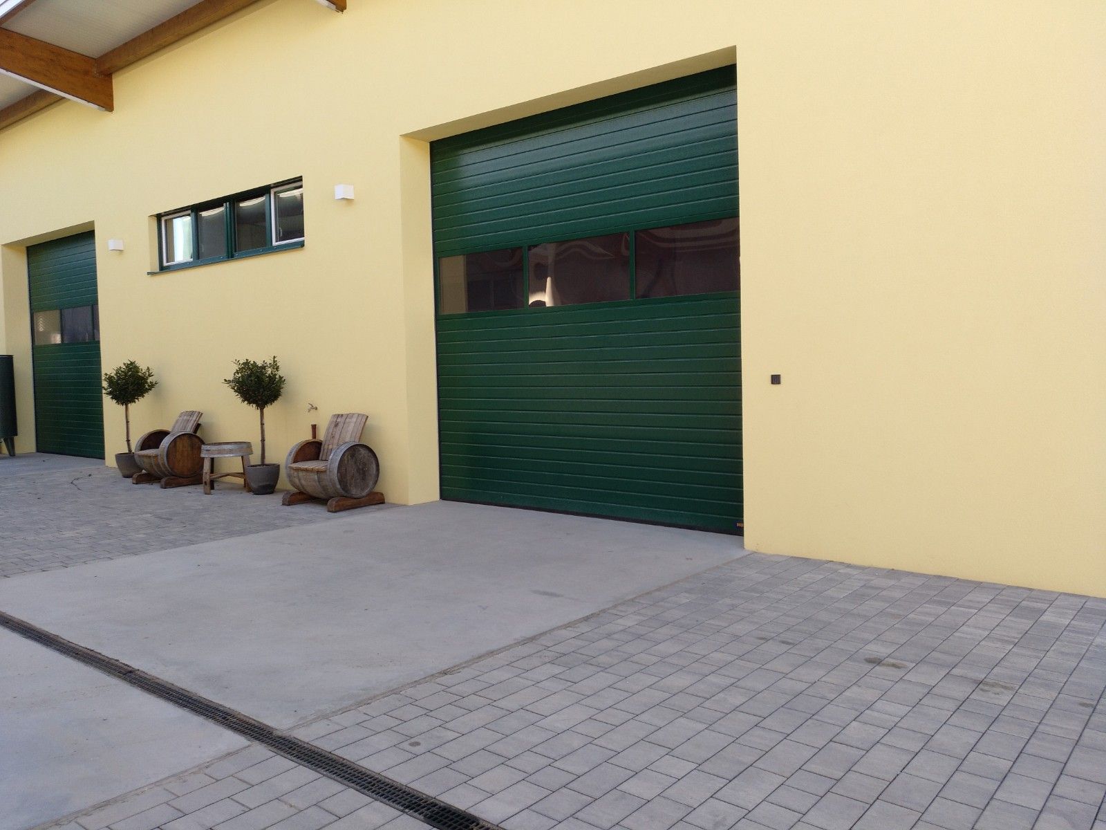 Yellow building with green gates and wooden furniture outside.