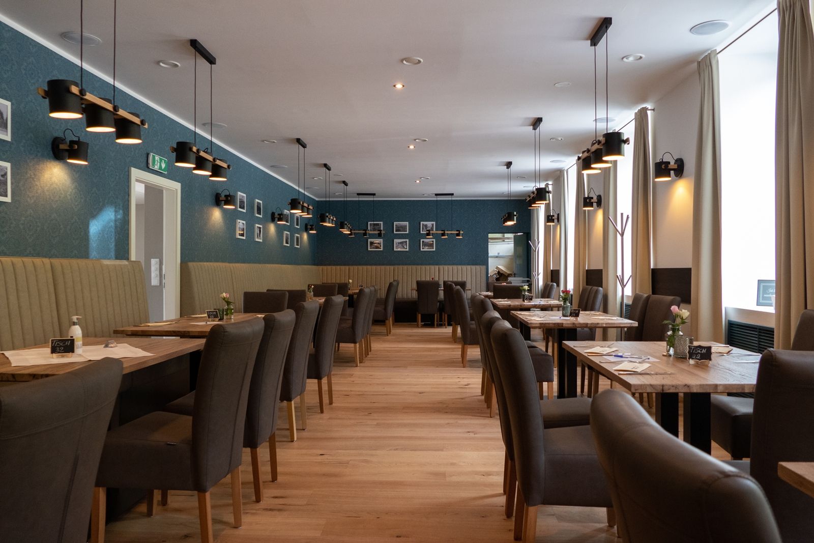 Interior view of an elegant restaurant with wooden floor, gray chairs and blue walls.