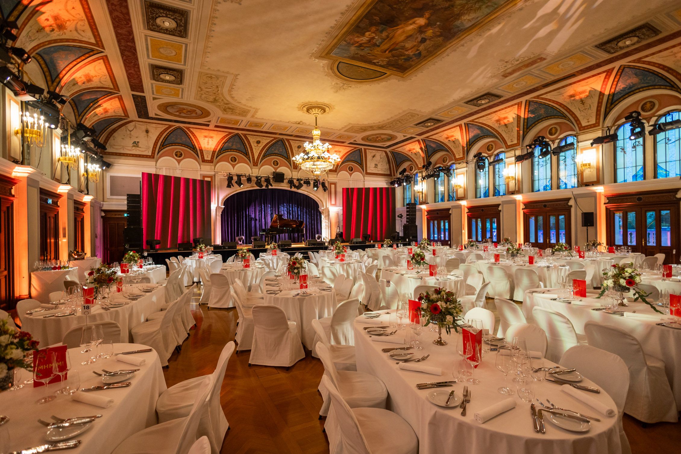 Elegant ballroom with set tables and stage at the Congress Center Baden.