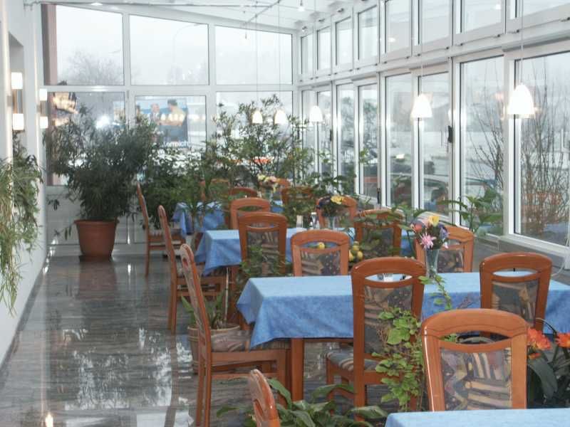 A winter garden with tables, blue tablecloths and lots of plants.