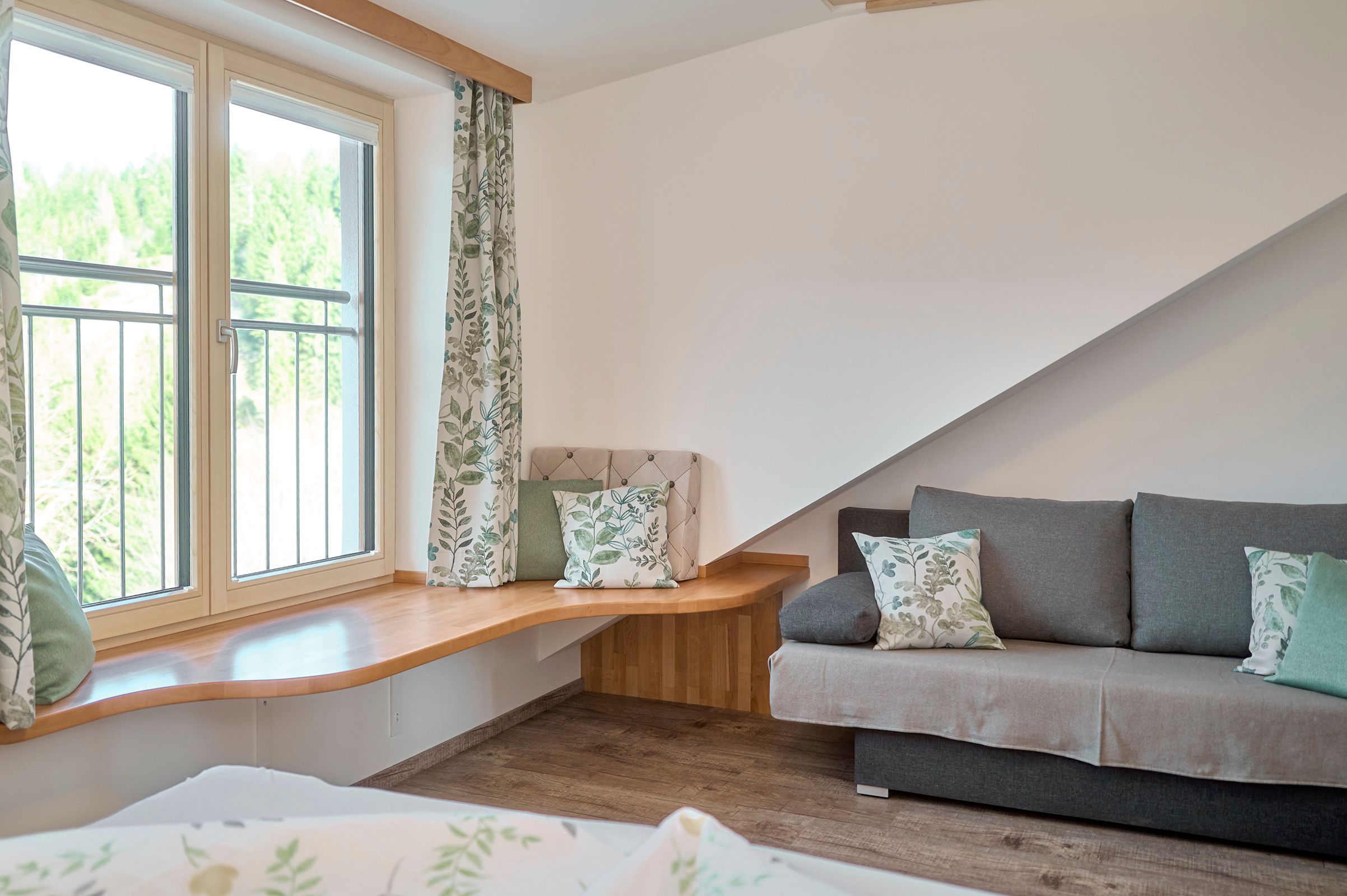 Living room with large window, gray sofa and wooden floor.