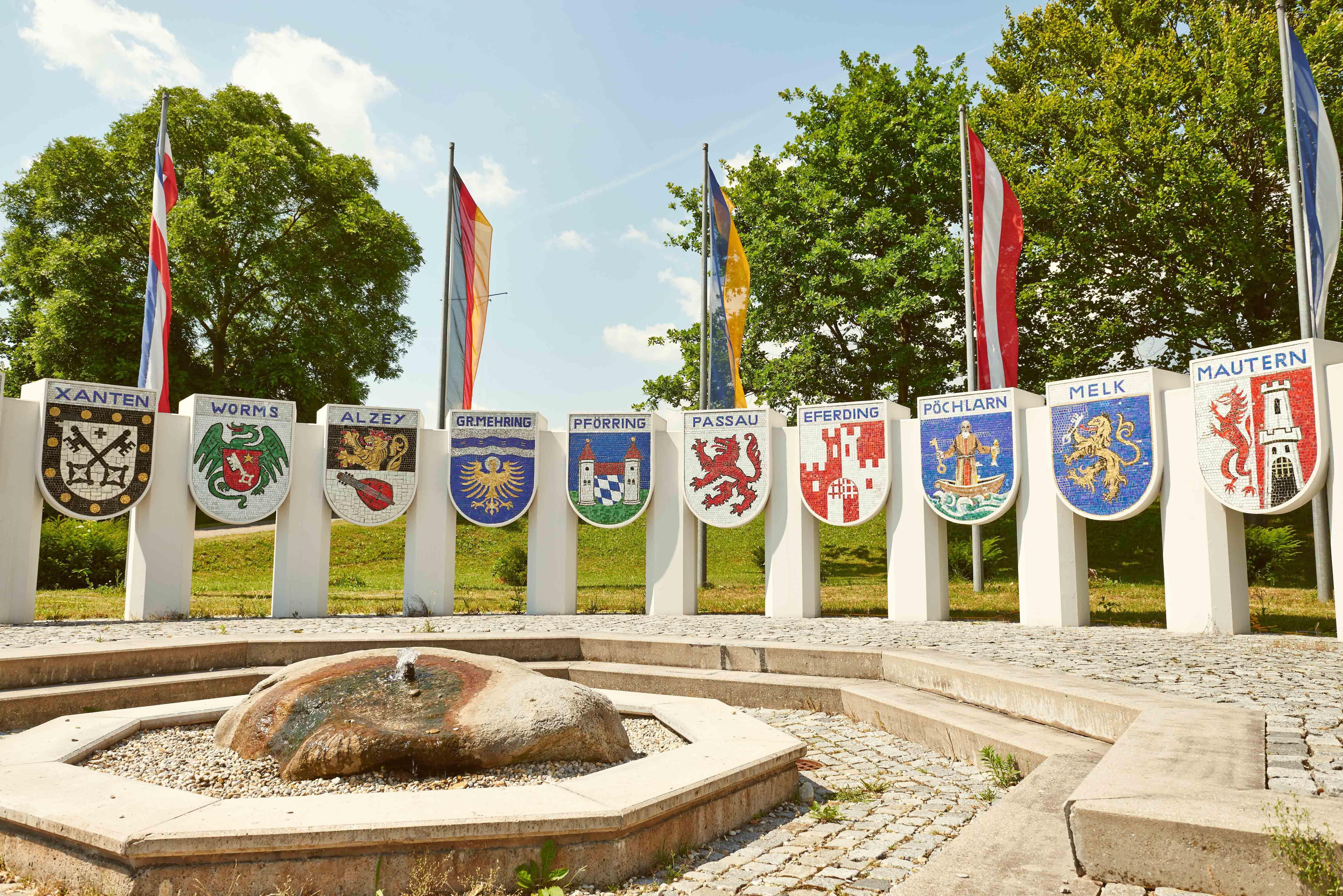 Nibelungen monument with coats of arms of various towns and flags in the background.