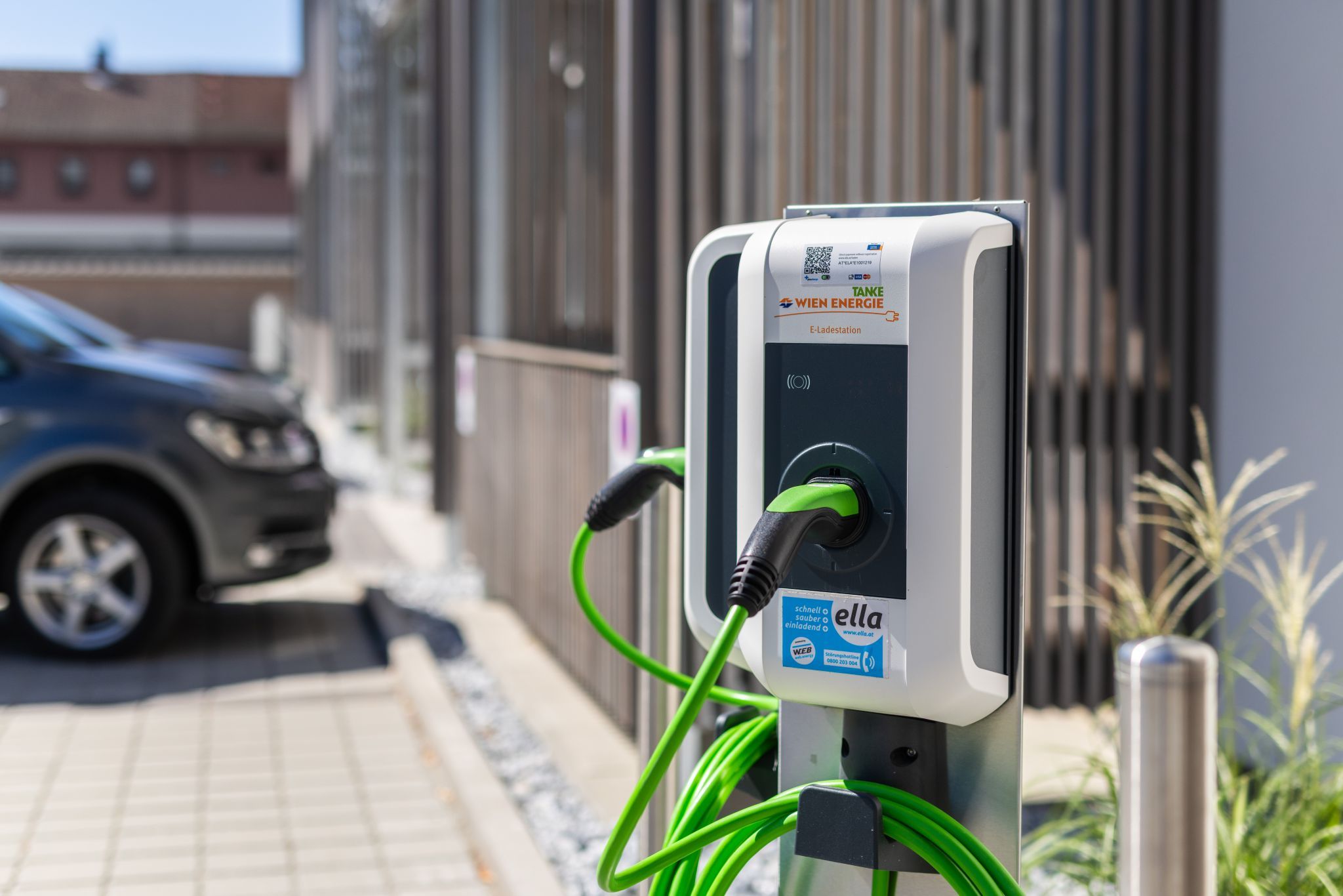 An outdoor Wien Energie electric vehicle charging station with a green cable.