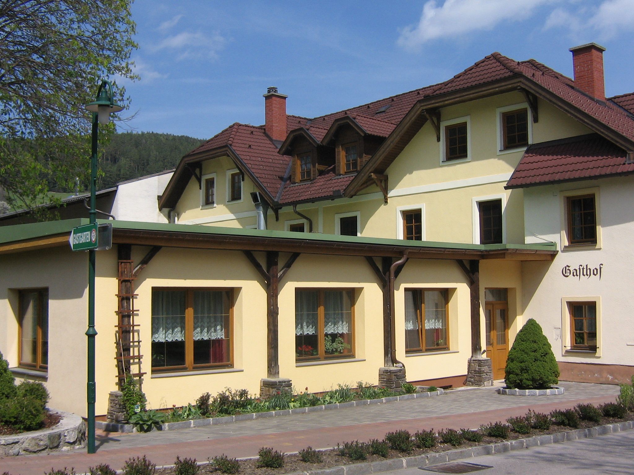 A traditional inn with a yellow façade and red roof tiles.
