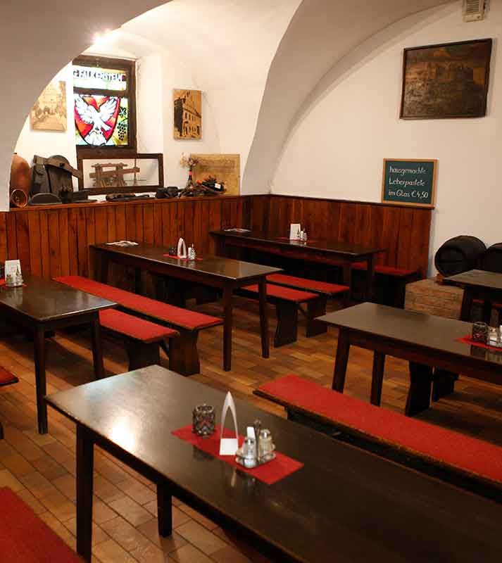 Interior view of a traditional Viennese inn with wooden tables and red benches.