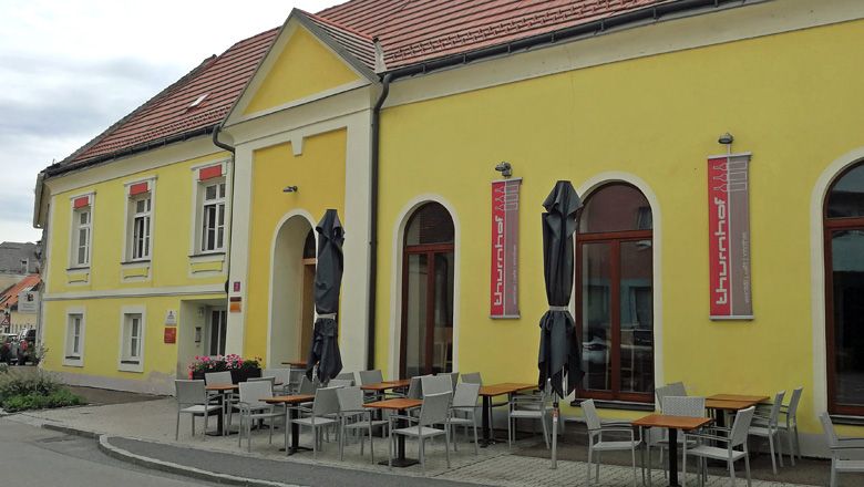 Yellow building with terrace and tables in front of the Thurnhof wine bar in Horn.