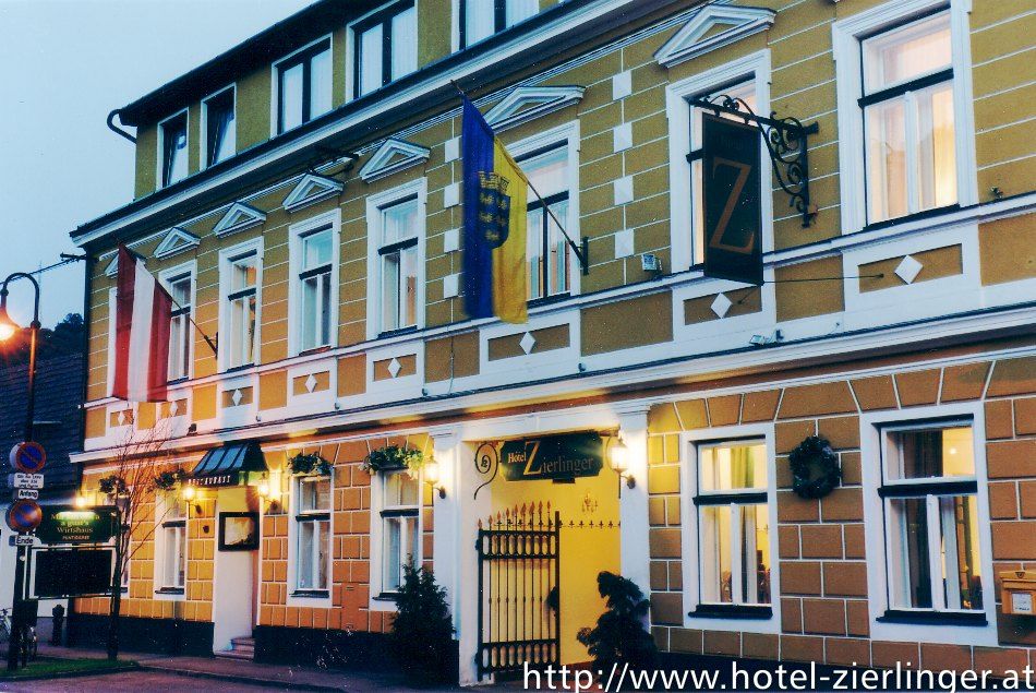 Exterior view of the Hotel Zierlinger with yellow façade and flags.