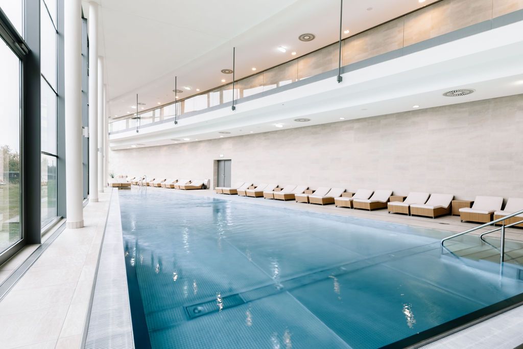 Interior view of a modern spa area with pool and loungers.
