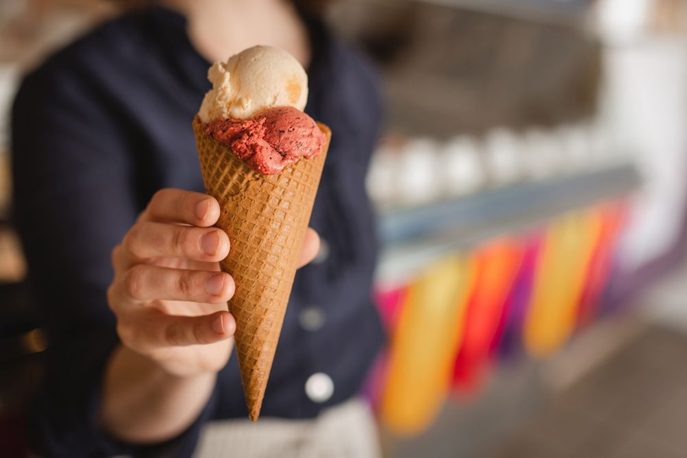 Person holding an ice cream cone with two scoops of ice cream.