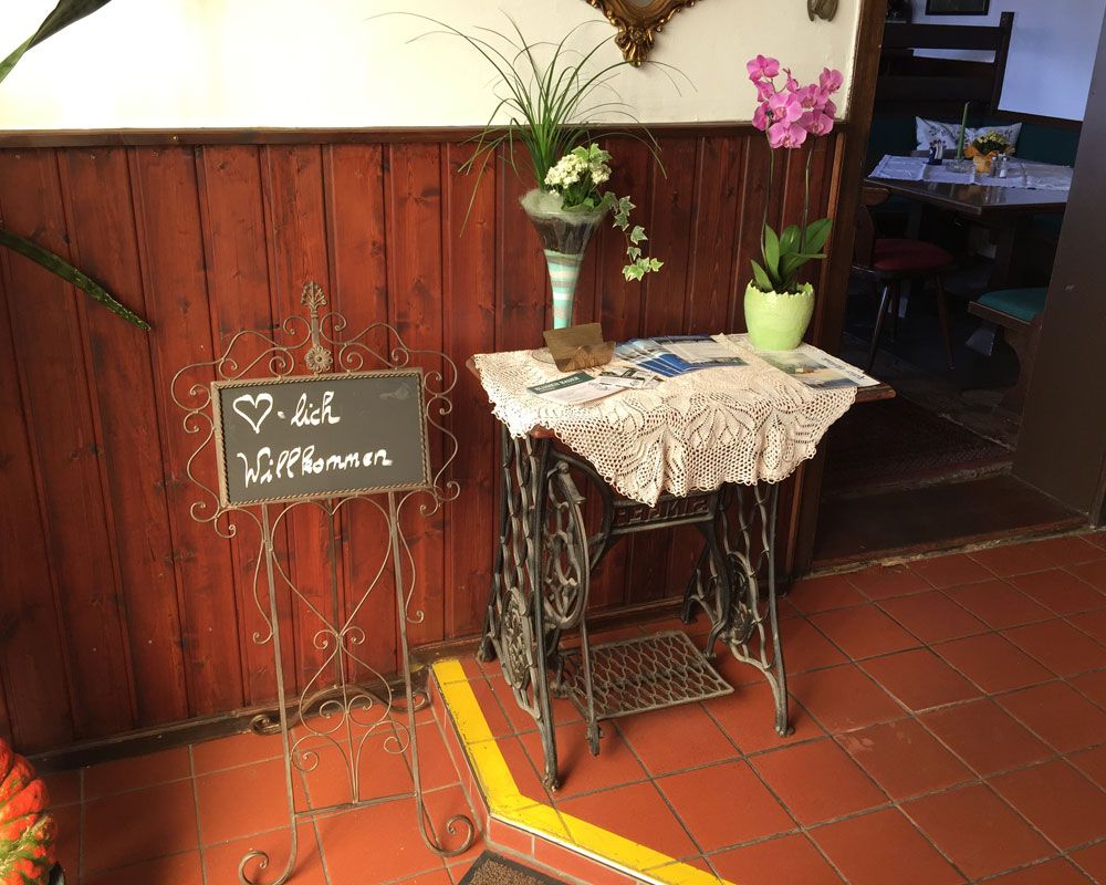 Entrance area of a pub with welcome sign and flowers.