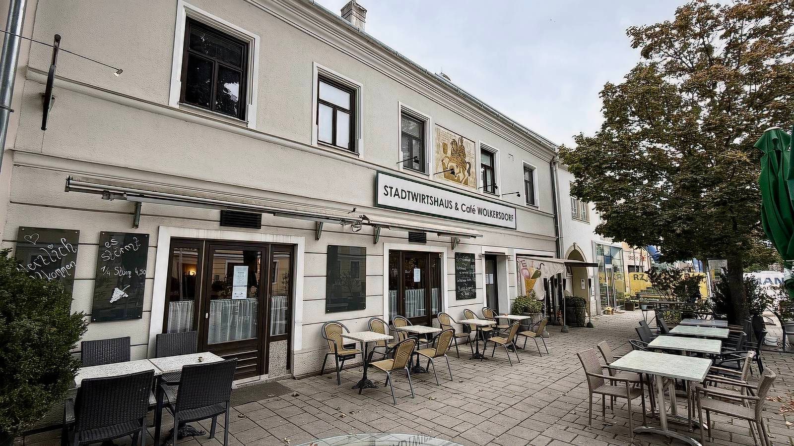 Exterior view of a café with tables and chairs on the sidewalk.