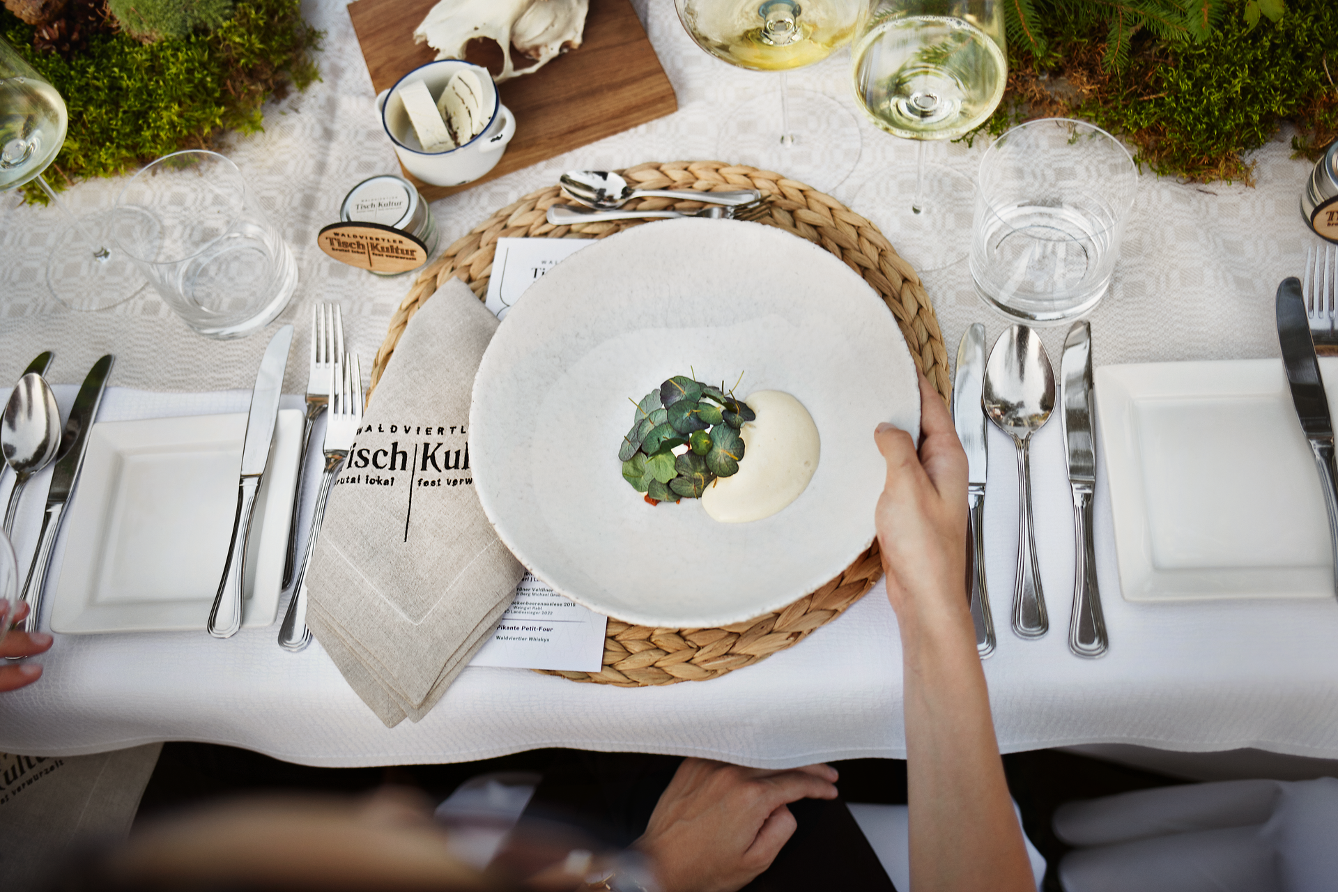 Ein liebevoll gedeckter Tisch inmitten der Natur lädt dazu ein, die kulinarischen Köstlichkeiten der Region zu genießen. Frische Kräuter und regionale Zutaten harmonieren perfekt auf dem Teller und versprechen ein unvergessliches Geschmackserlebnis. Die ruhige Atmosphäre und die umgebende Waldlandschaft schaffen einen idealen Ort für entspannte Stunden.