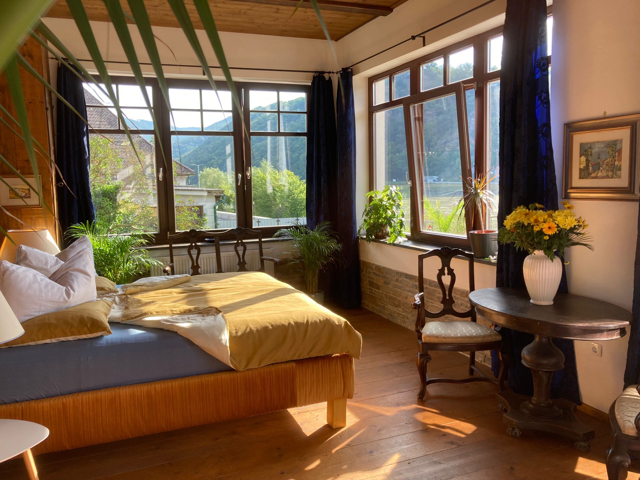 Cozy bedroom with large windows, plants and antique furniture.