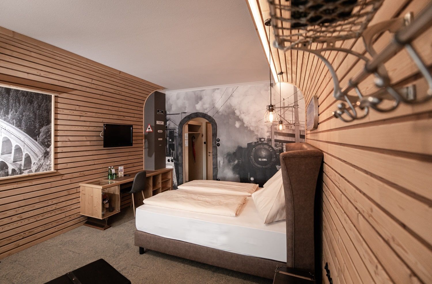 Hotel room with wooden walls, a double bed and a large mural of a steam locomotive.