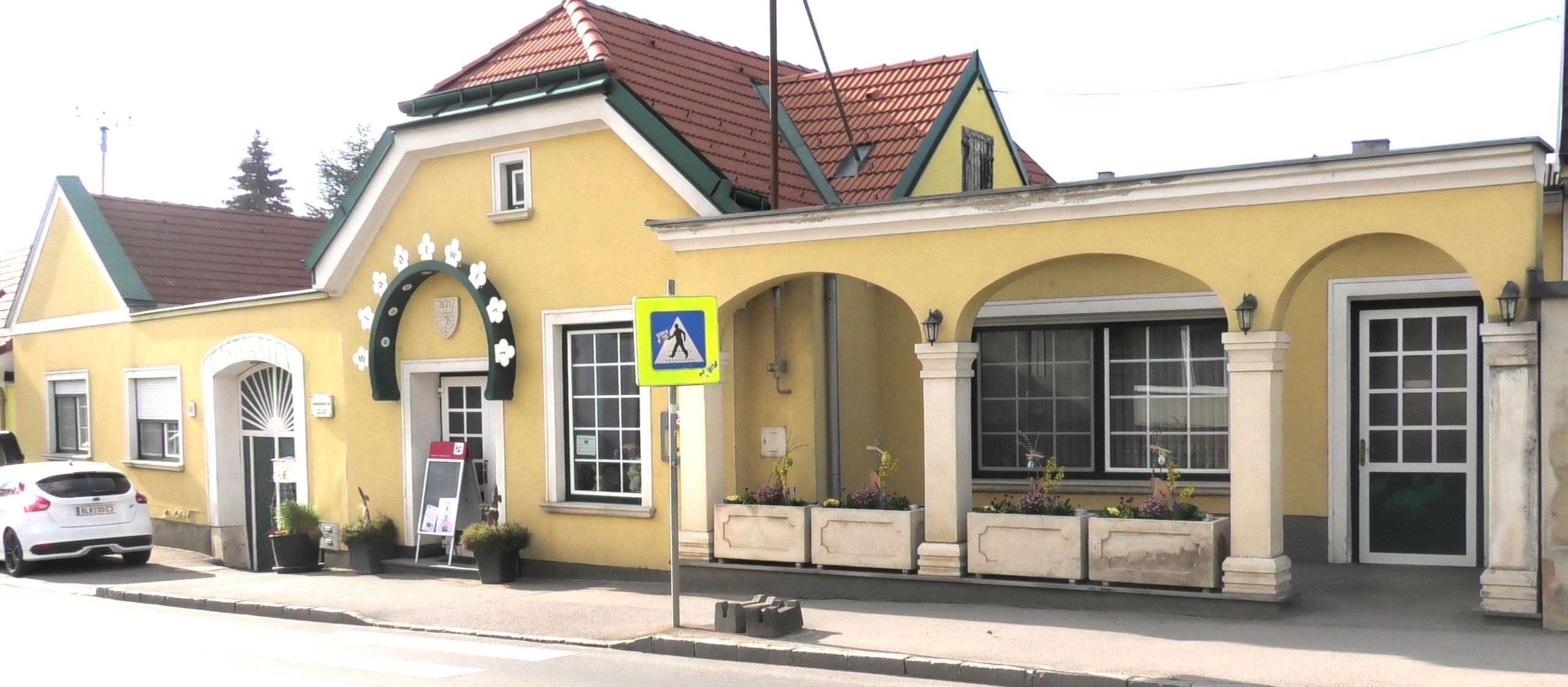 Exterior view of a yellow building with arcades and a red roof.