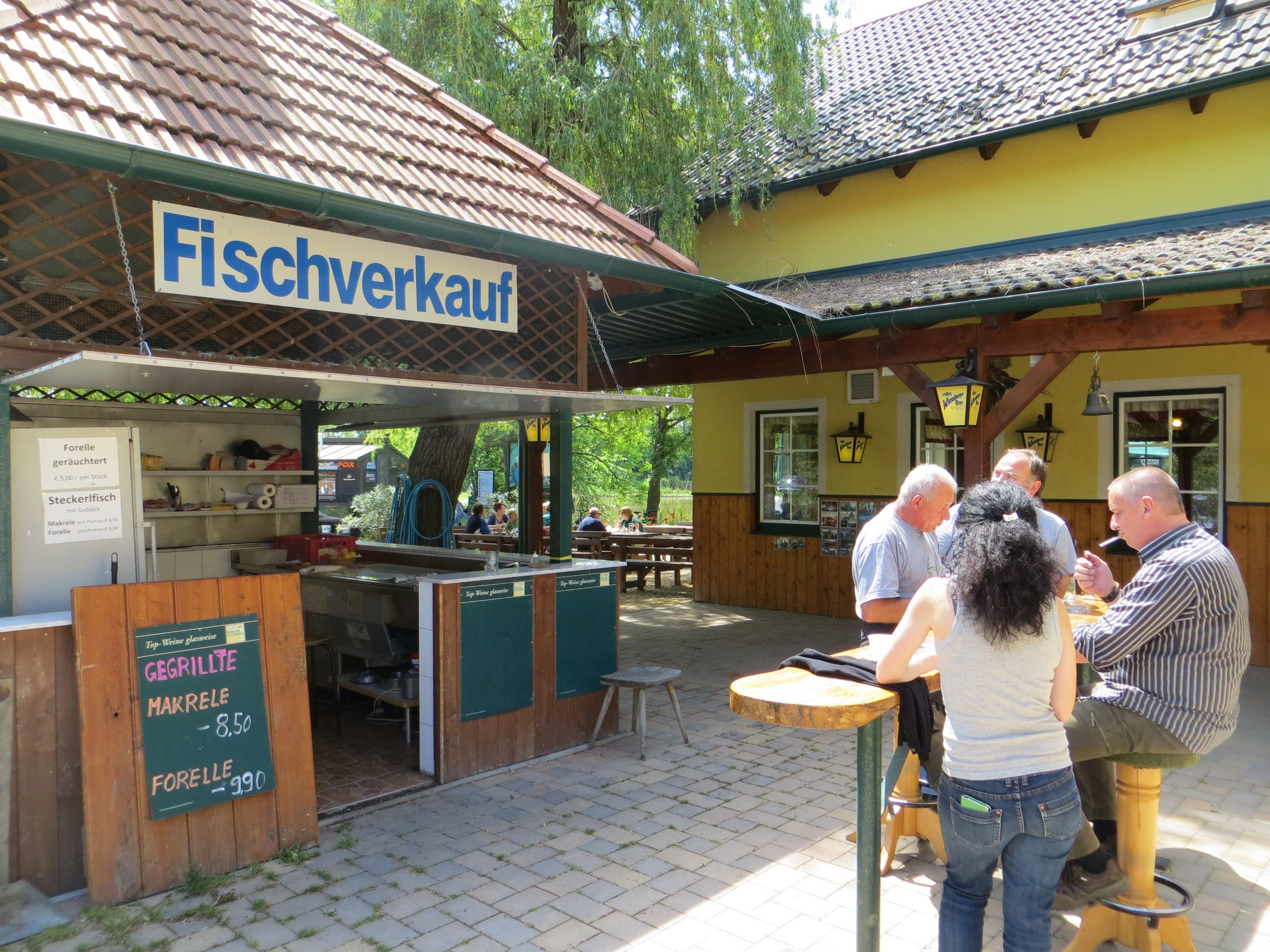 A fish stall with people eating at a table.