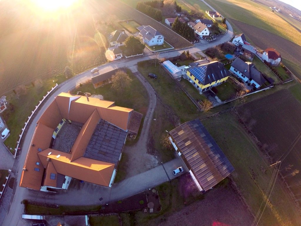 Aerial view of a village with houses, streets and fields at sunset.