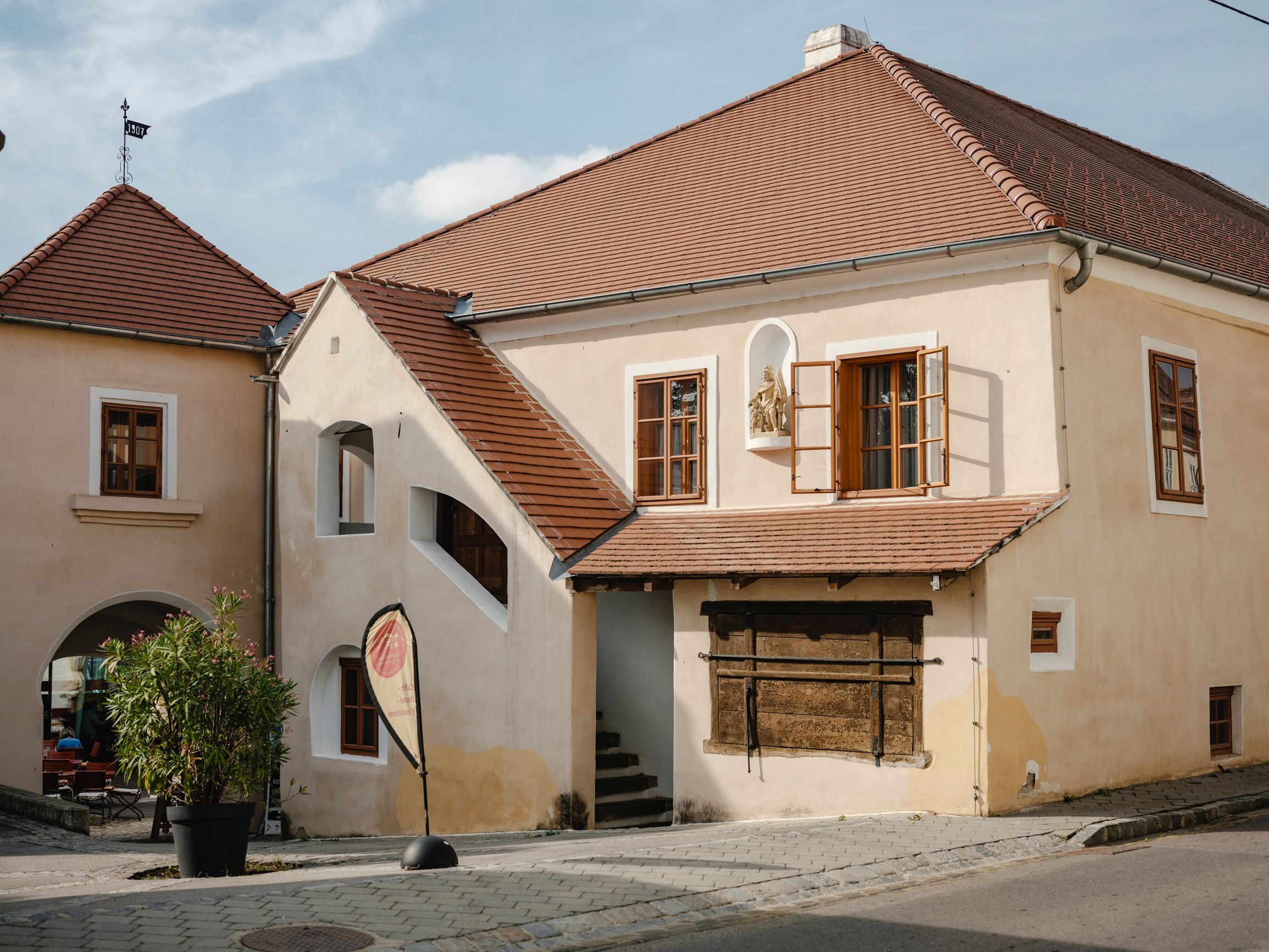 Historic building with red tiled roofs and open windows.