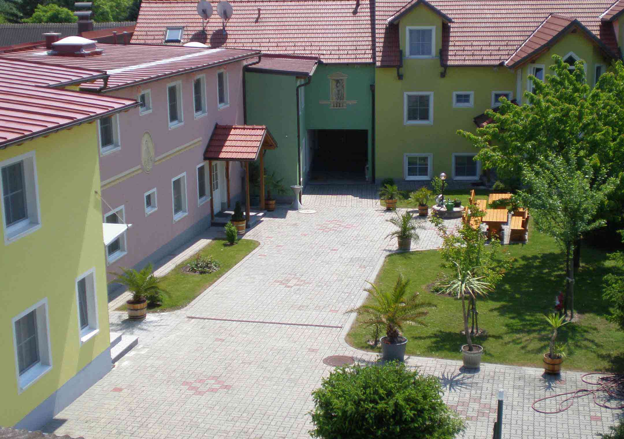 Inner courtyard of a guesthouse with colorful buildings, plants and seating area.
