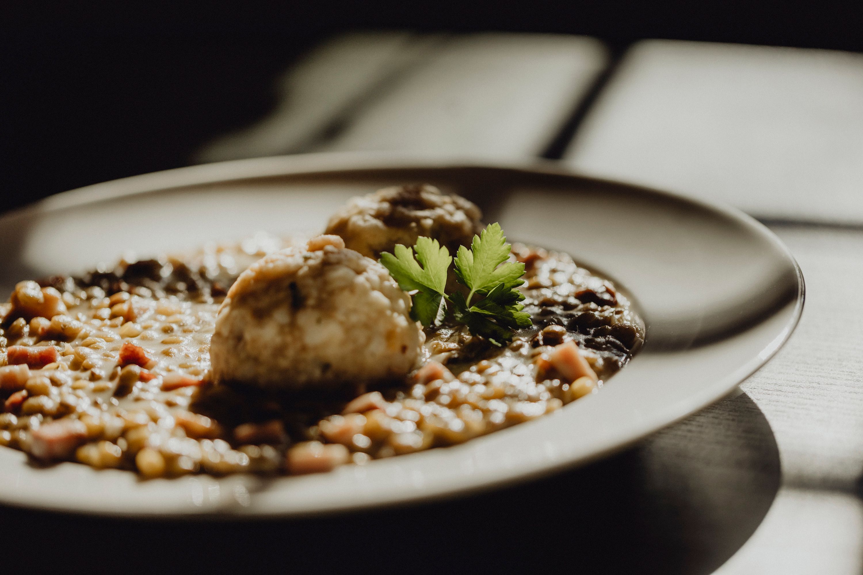 Close-up of a plate with lentil dish and dumplings, garnished with parsley.