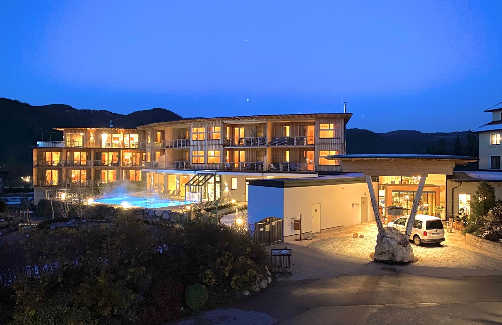Hotel Molzbachhof at night with illuminated windows and pool.