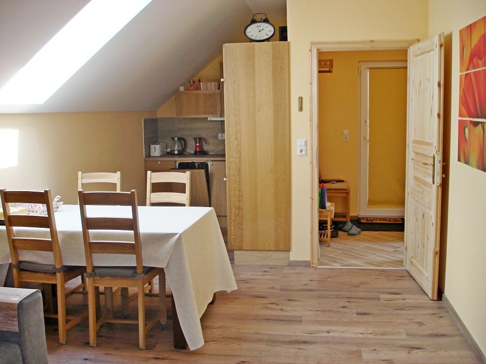 Dining area of a vacation apartment with table, chairs and kitchenette.