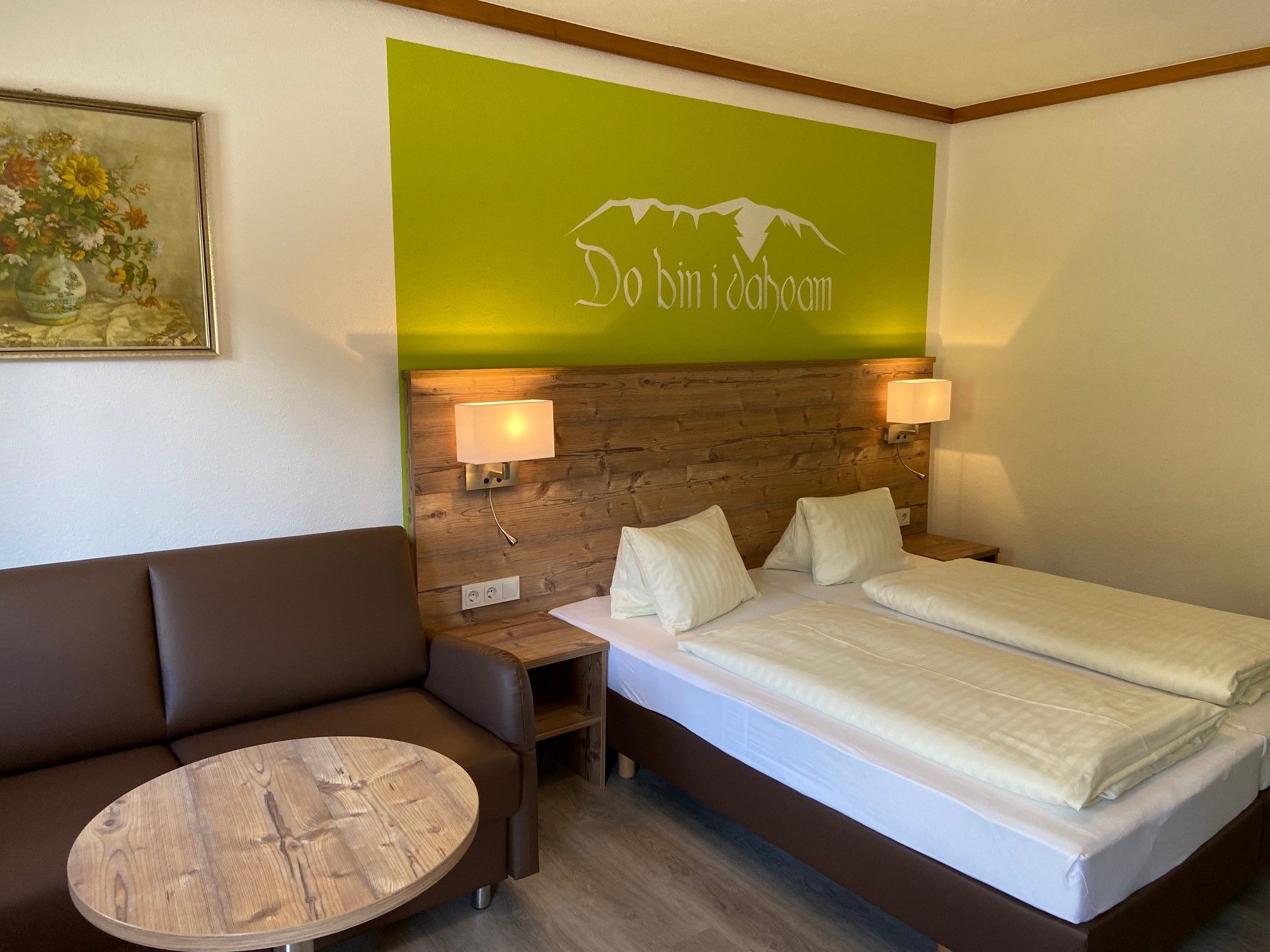 Cozy double room with wooden furniture, sofa, table and wall decoration.