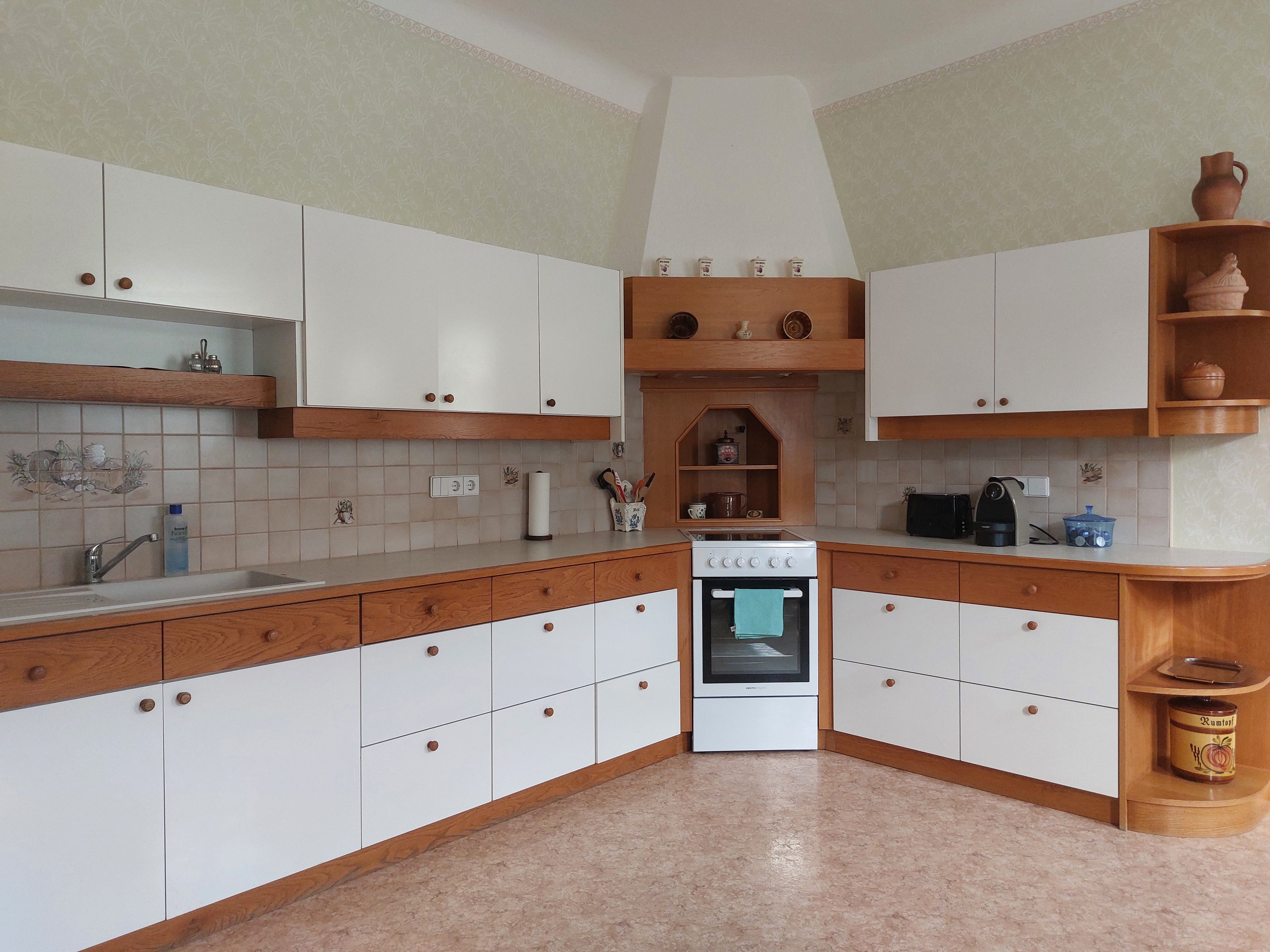 Kitchen with white and wood-colored cabinets, stove and sink.