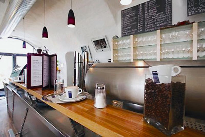 Interior view of a café with counter, coffee machine and glasses.