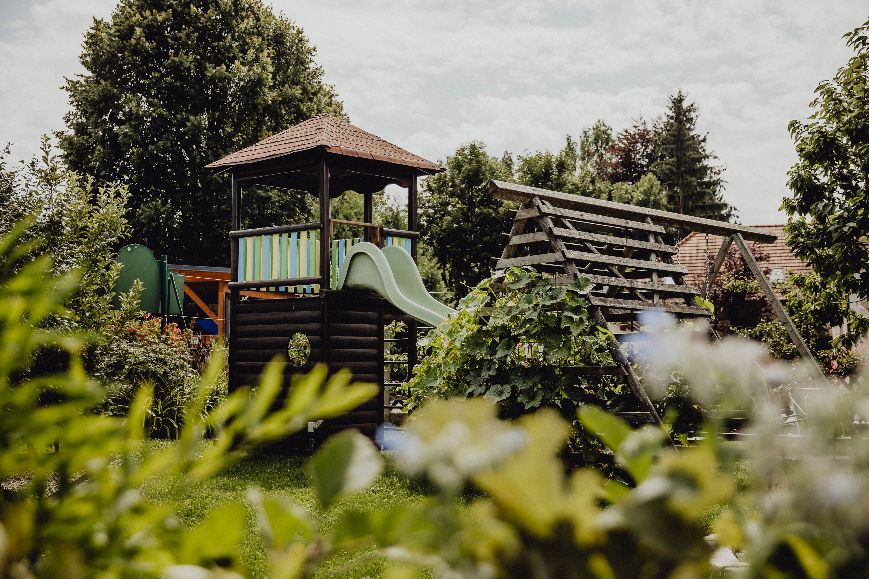 A playground with a slide and climbing frame in a green garden.