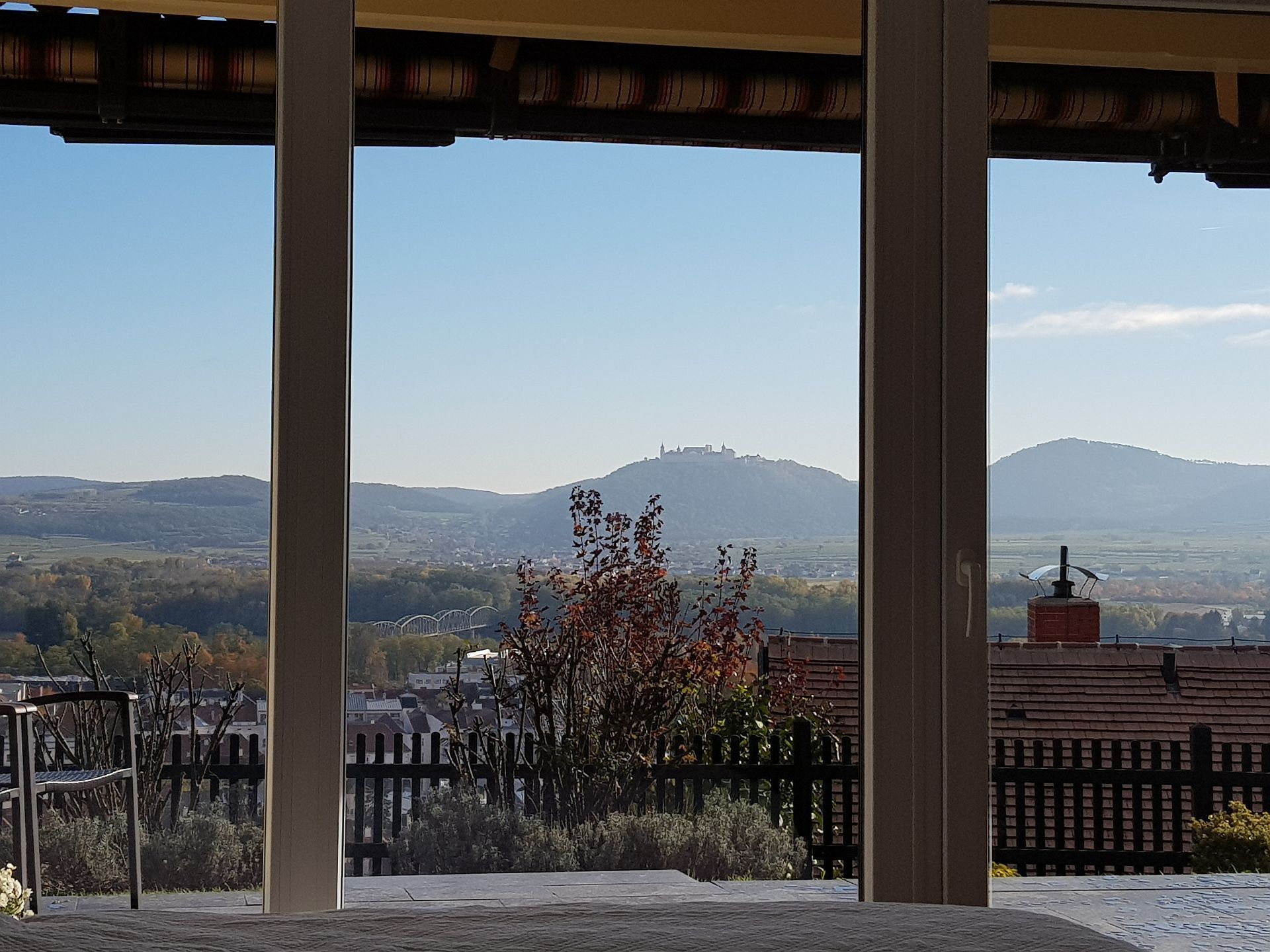 View from a window of a hilly landscape with a monastery on a hill in the background.