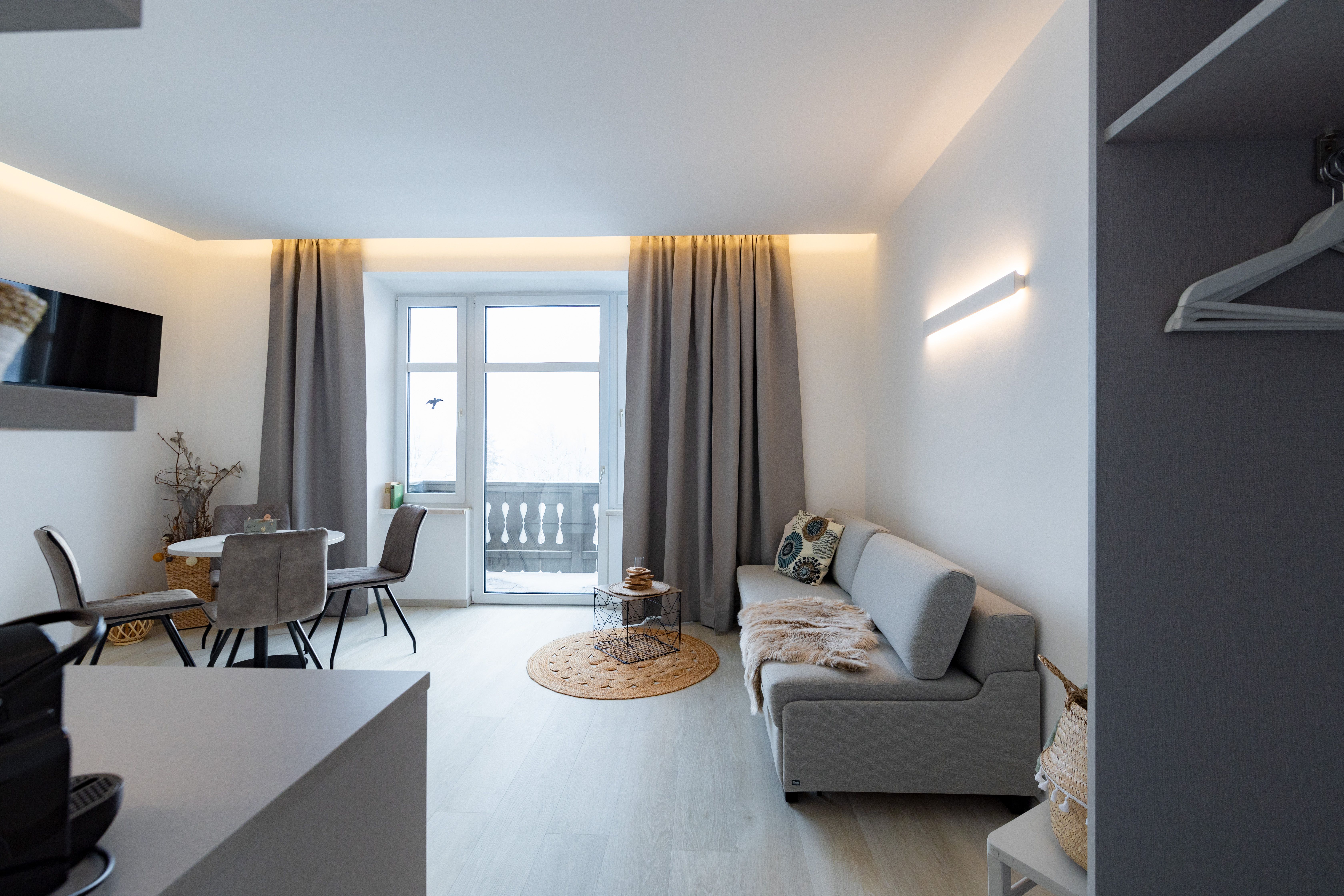 Modern living room with gray sofa, dining table and balcony.