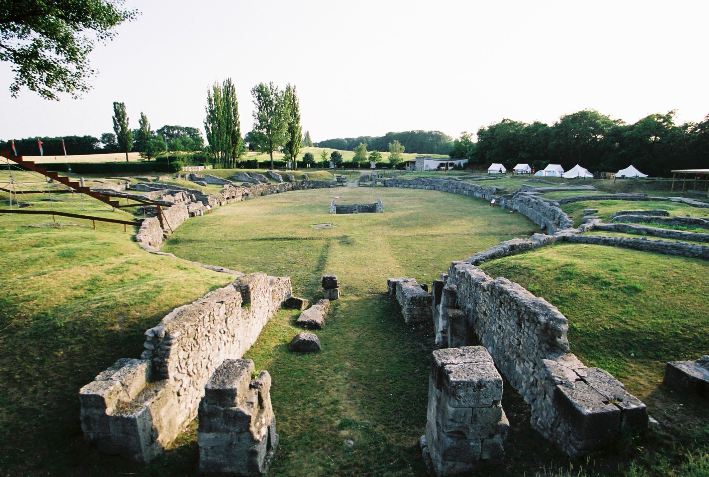 Ruins of an ancient amphitheater with surrounding green landscape.
