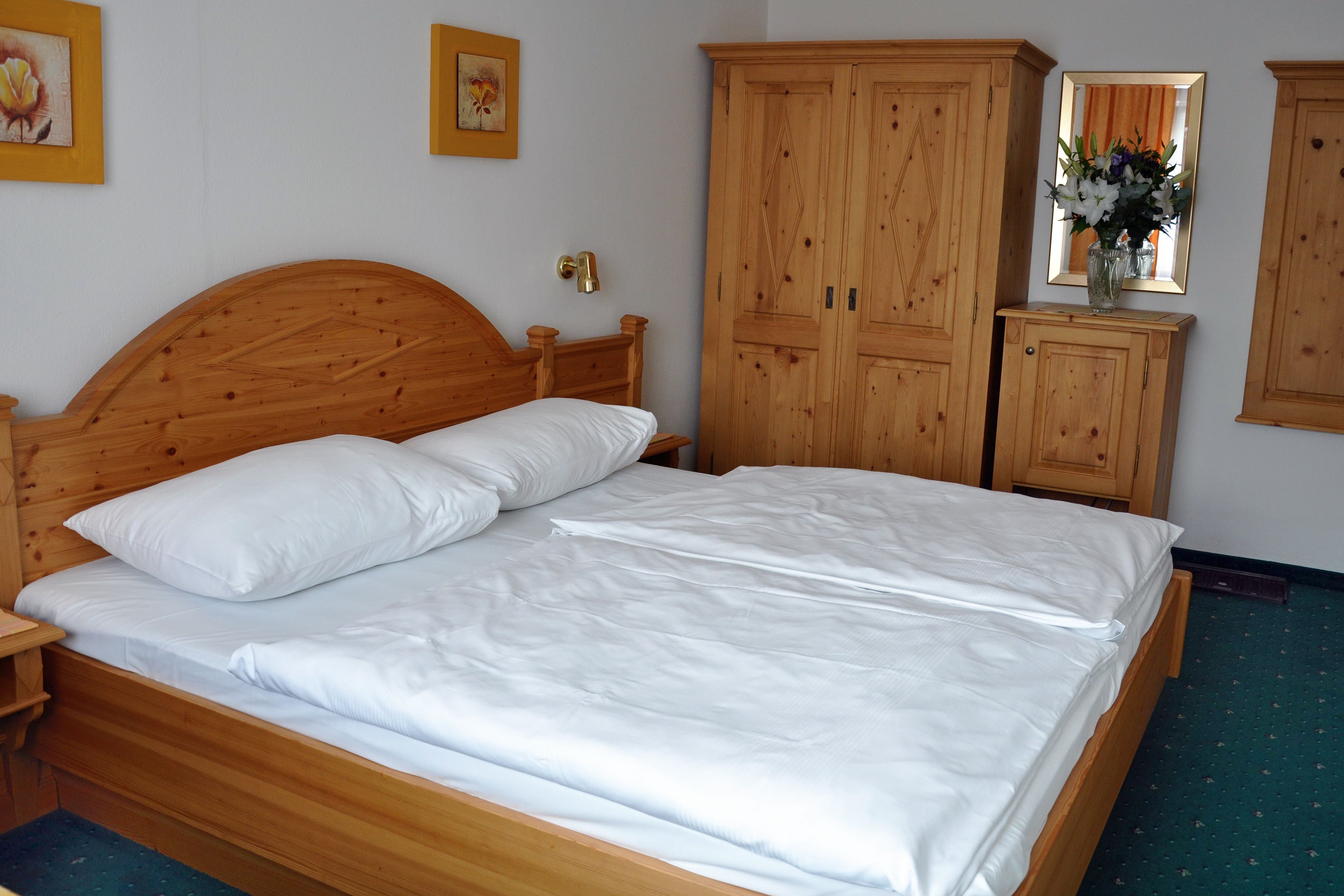Comfort room with solid wood furniture, double bed, closet and flowers on chest of drawers.
