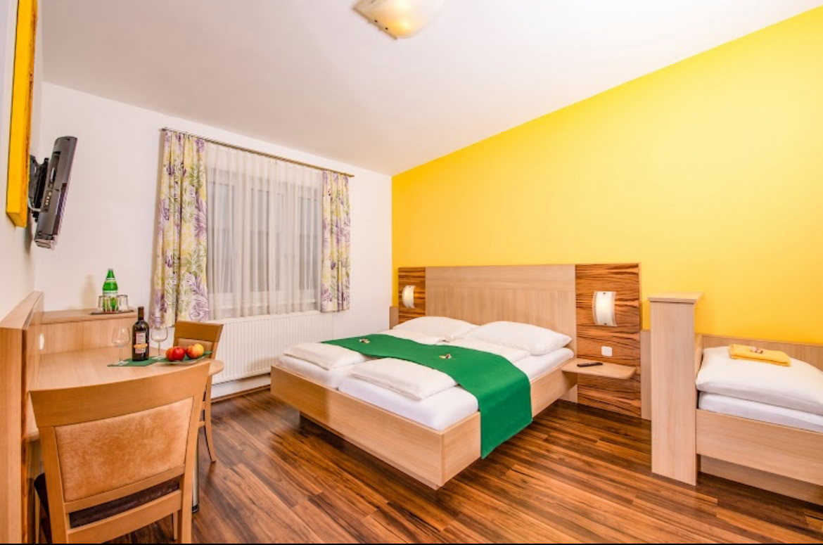 Double bed in a room with a dark floor and yellow back wall