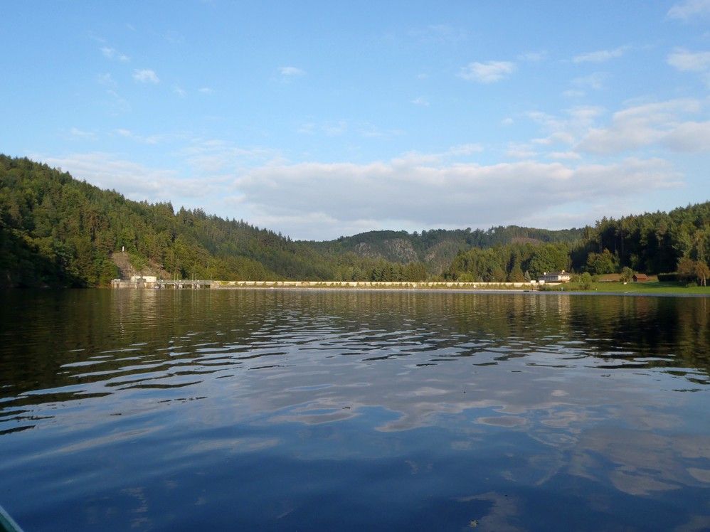 Thurnberg reservoir with wooded hills and dam in the background.