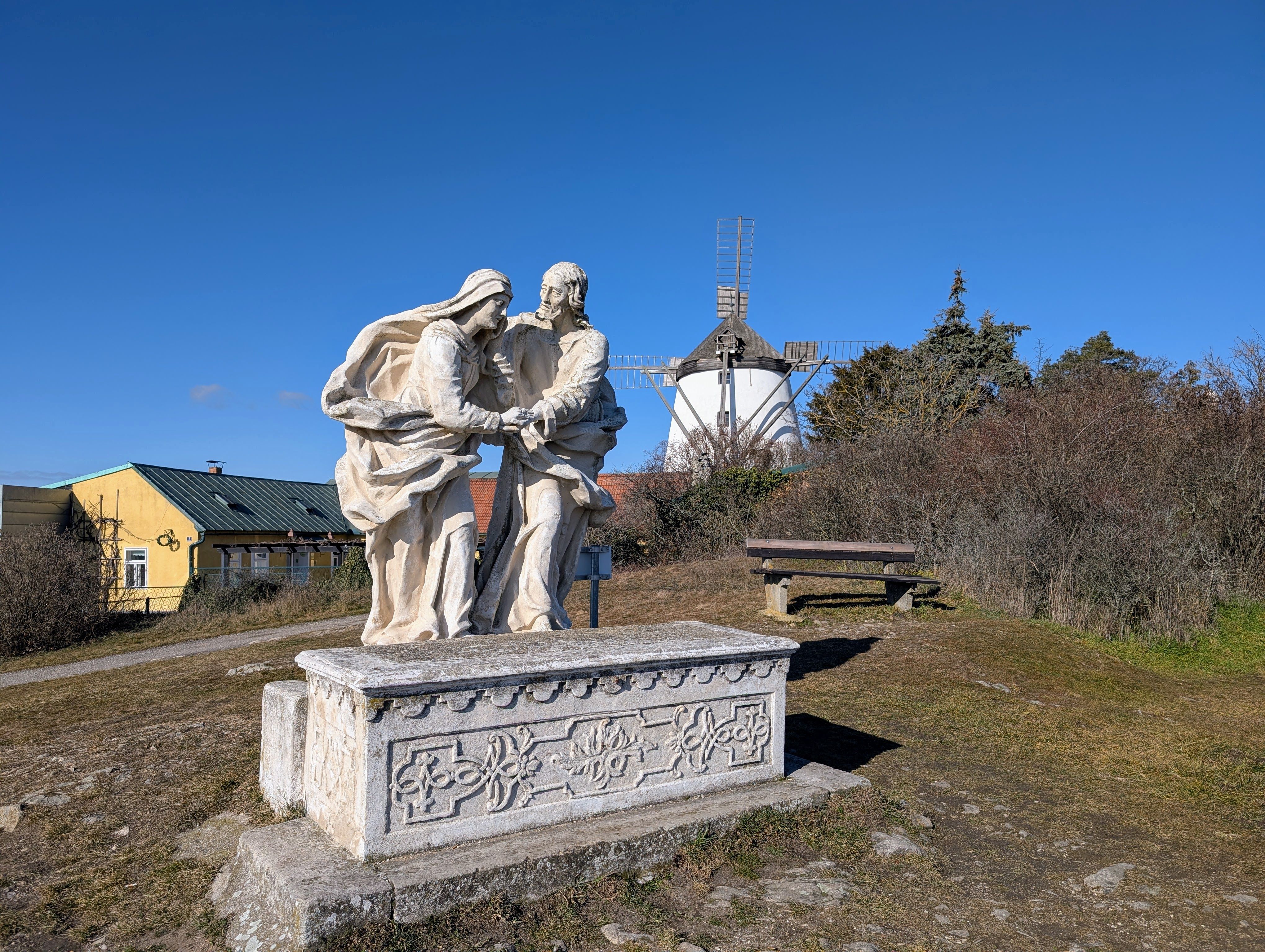 Stone sculpture on a hill with a windmill in the background.