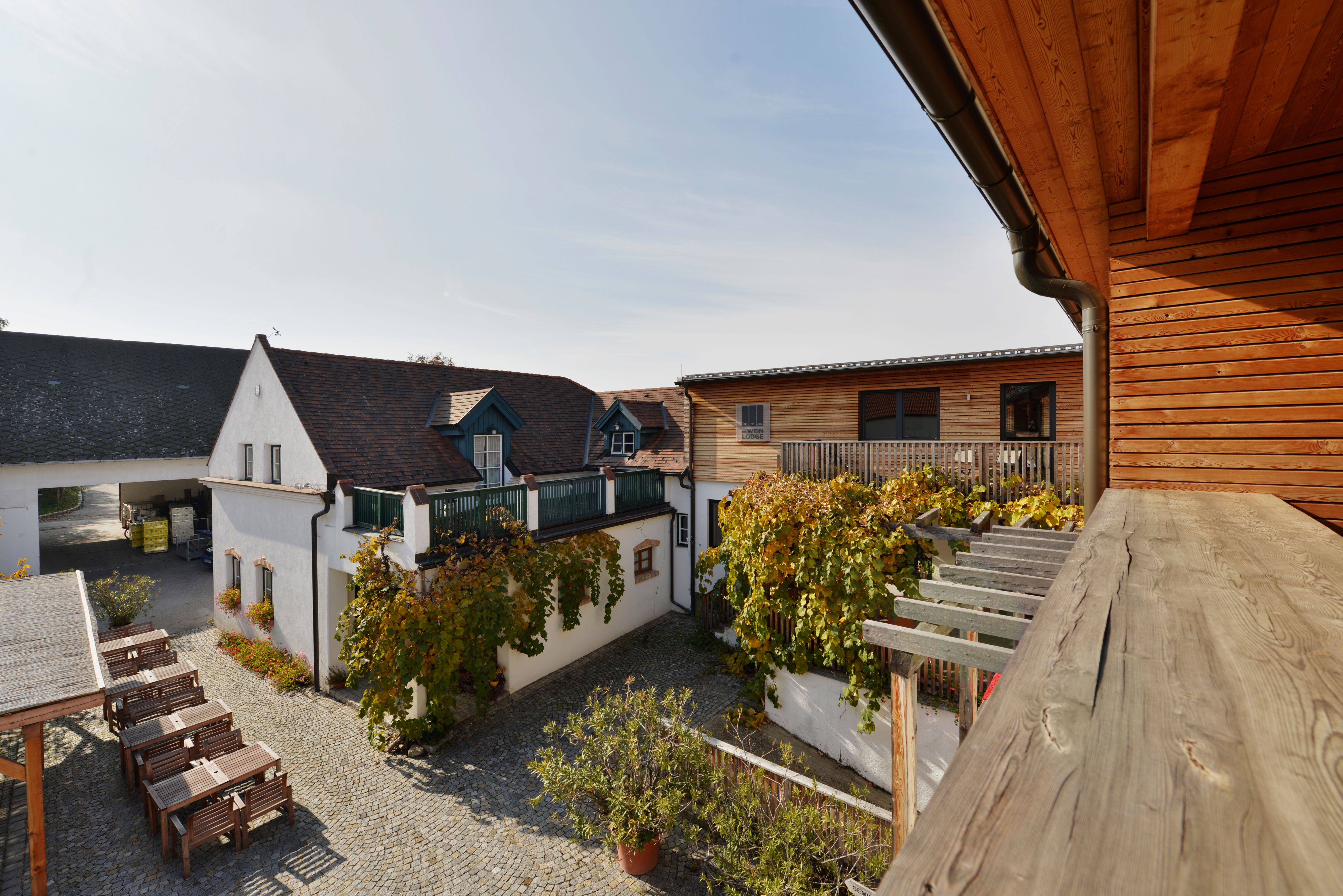 Inner courtyard of a winery with wooden buildings and vines.