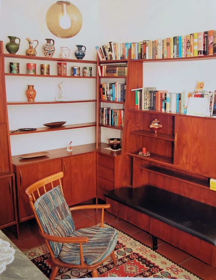 Cozy reading corner with wooden shelves, books and an armchair.