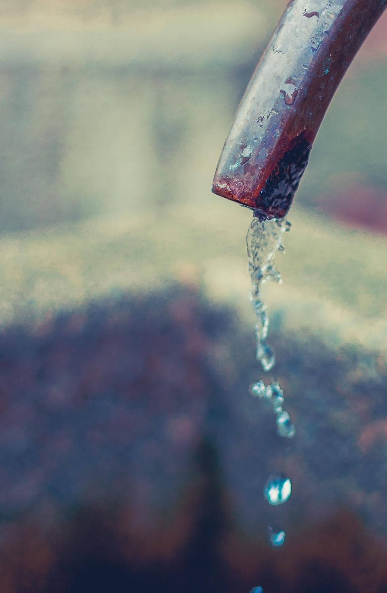 Close-up of a jet of water flowing out of a metal pipe.