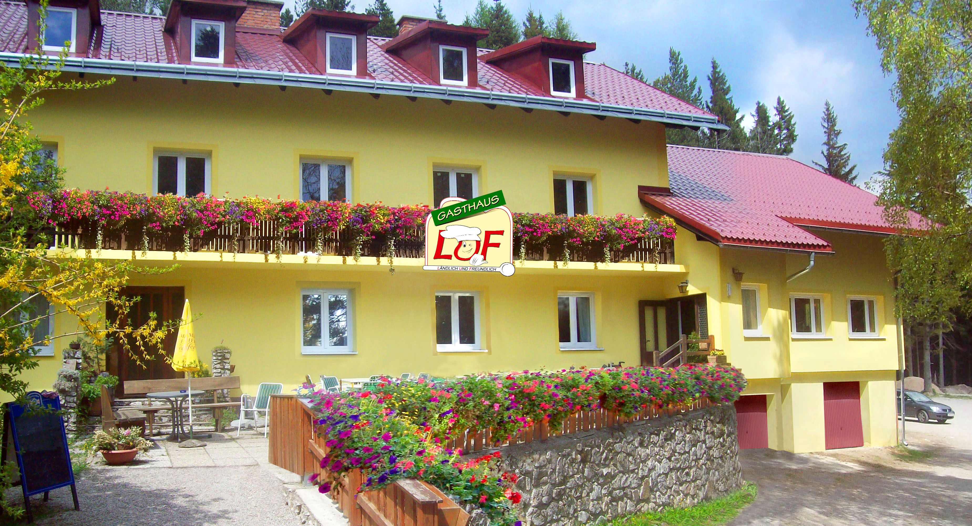 Yellow inn with red roofs and blooming flowers on the balcony.