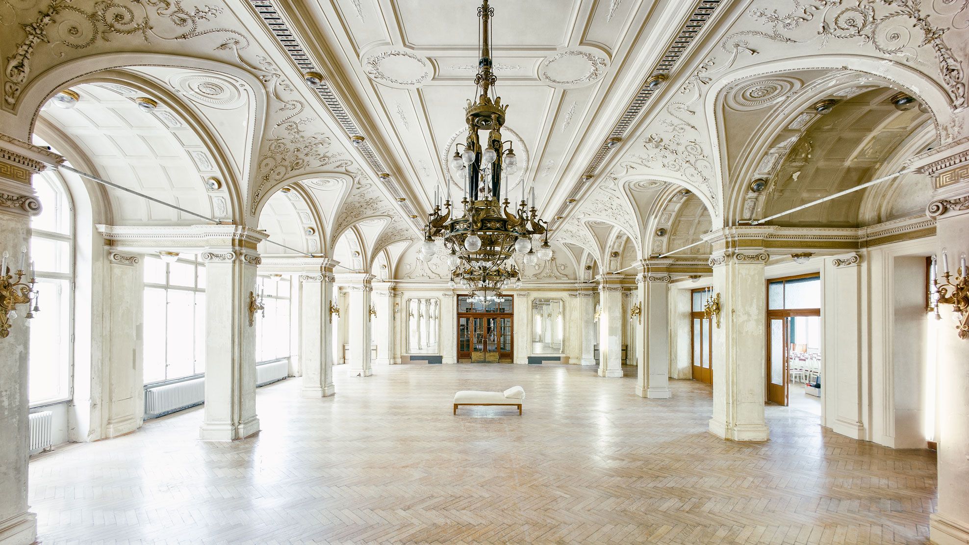 Large, elegant dining room with ornate ceilings and chandeliers in the Südbahnhotel.