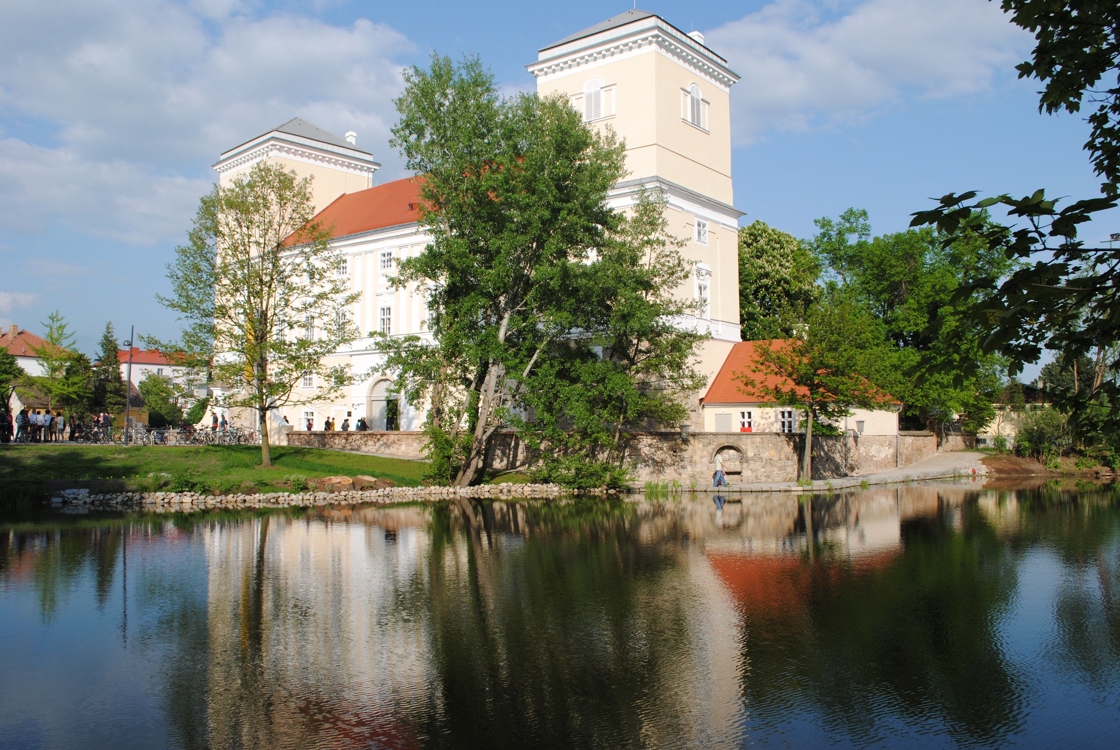 Wolkersdorf Castle with reflection in the water and surrounded by trees.